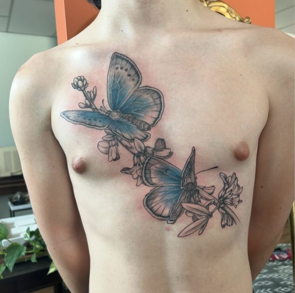 butterfly tattoo on chest with fine lines and blue highlights