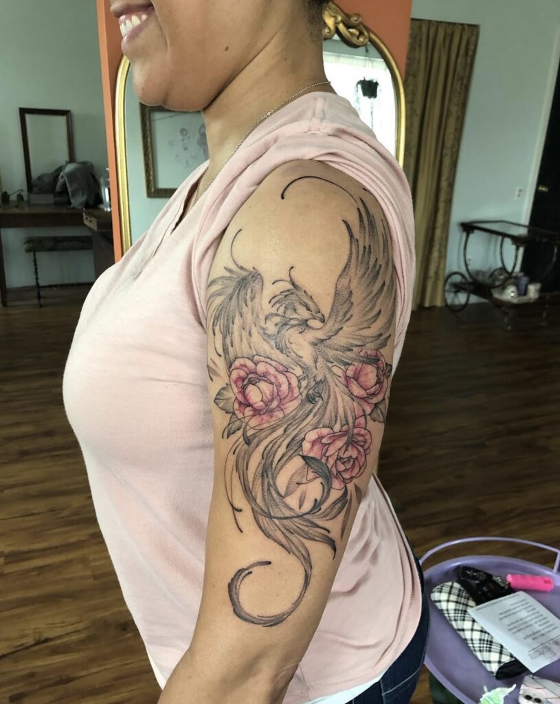 black and grey phoenix with colorful roses on upper arm